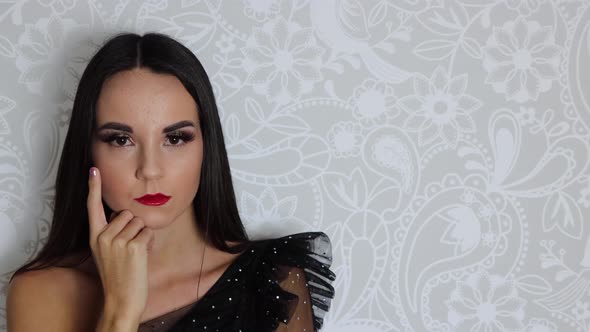 A young attractive woman wearing a black elegant dress with long brown hair alt