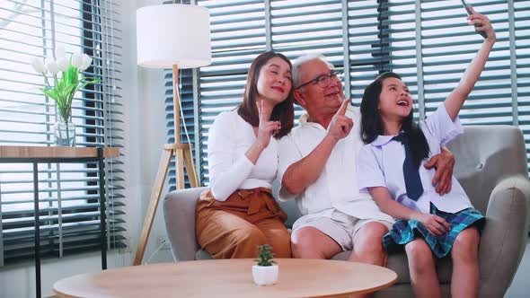 Granddaughter using a smartphone to taking a selfie photo with grandpa and mom. alt