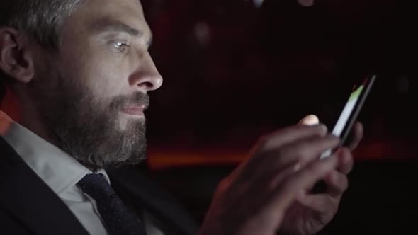 Businessman Typing on Mobile Phone in Car alt