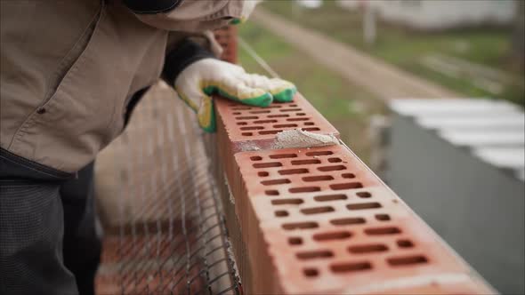 A Master Mason Is Laying a Red Brick Wall. The Master at the Construction Site Is Laying a Brick alt