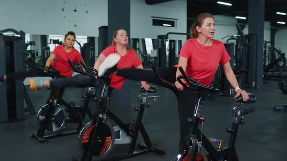 Athletic Women Group Making Stretching Training on Spinning Stationary Bike Routine in Gym Indoors alt
