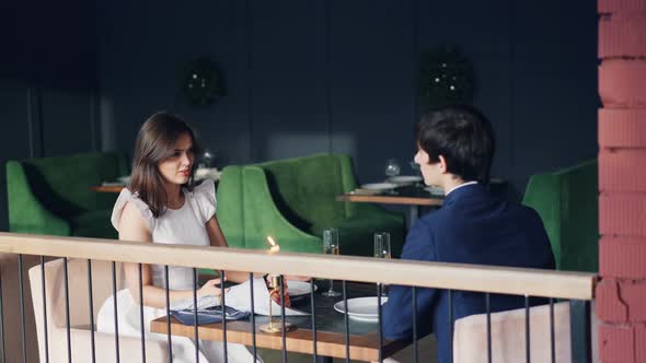 Offended Young Lady Is Fighting with Her Husband During Date in Restaurant alt