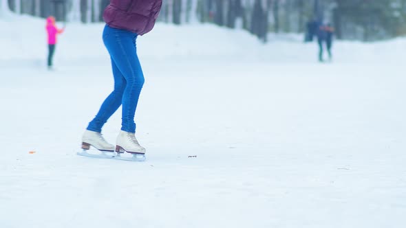 Young Lady with Ponytail in Jacket Spins on Skates on Rink