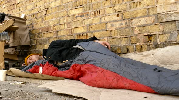 Homeless man sleeping near the cart with his stuff