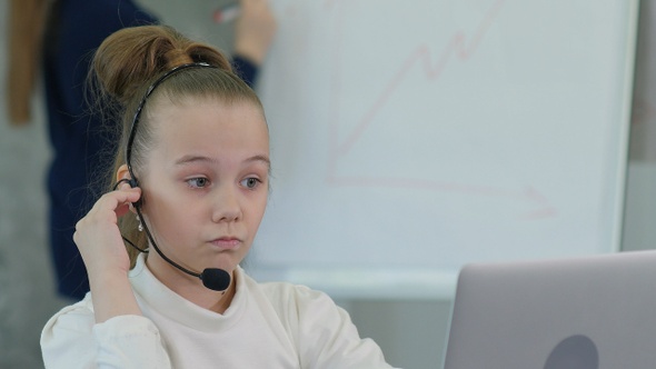 Pretty Little Girl Wearing Headset Using Laptop and Talking