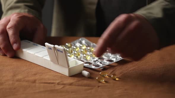man sorts pills by day of the week in a sorter alt