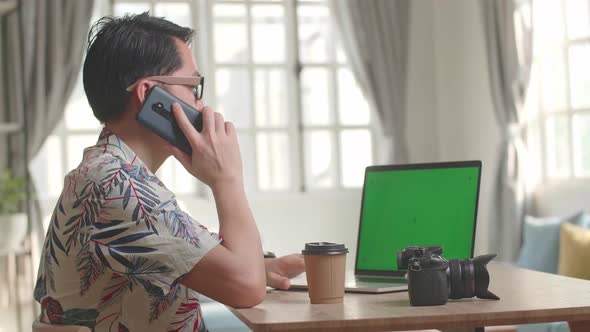 Photographer Talking On Mobile Phone With Green Screen Display Laptop Computer alt