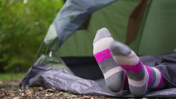 A Woman in Bright Multicolored Socks Lies in a Tent in the Woods
