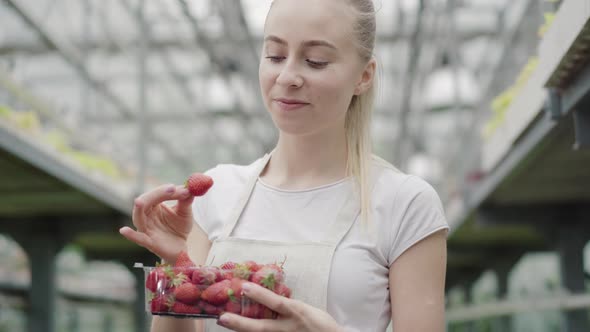 Camera Approaches To Beautiful Face of Young Caucasian Woman Biting Sweet Strawberry and Smiling at alt