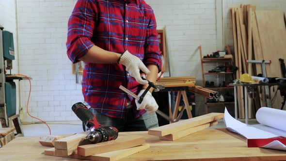 Carpenter uses lock tool to lock the wood on table before drilling in the workshop