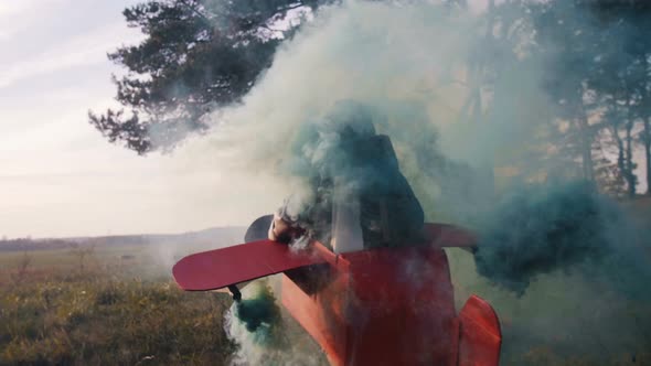 Camera Follows Happy Little Aviator Boy Running Outdoors in Fun Cardboard Plane Costume with Color alt