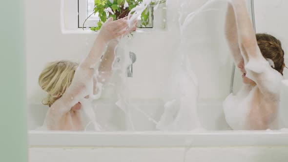 Kids Splashing Soap Suds In Bath alt