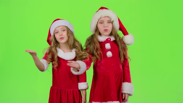 Children in Red Christmas Caps Send Air Kisses. Green Screen. Slow Motion alt