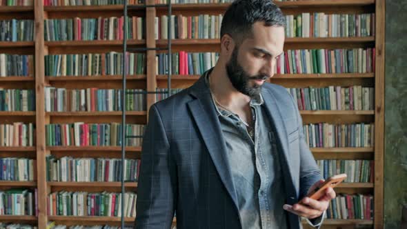Young Man With Mobile Phone In His Hands Enters In The Library alt