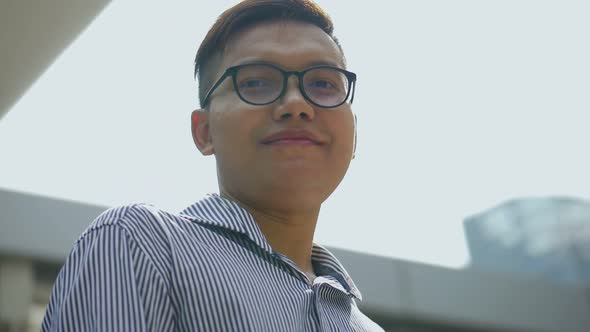 Asian businessman smiling and looking at camera standing on the urban city.