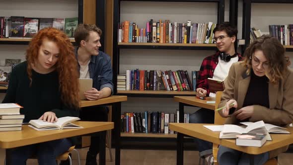 Intelligent Female and Male Students Learning Preparing for Exams in College Library Sitting By the alt