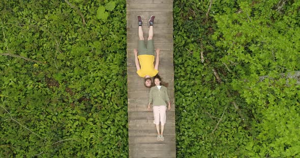 Couple of Lovers Lying on a Wooden Bridge in the Forest