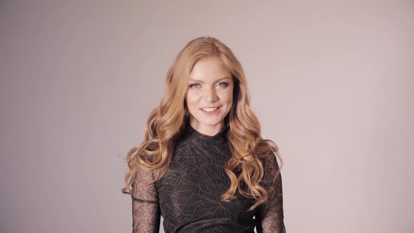 Blonde Pretty Lady in Black Dress Touching Gorgeous Curls