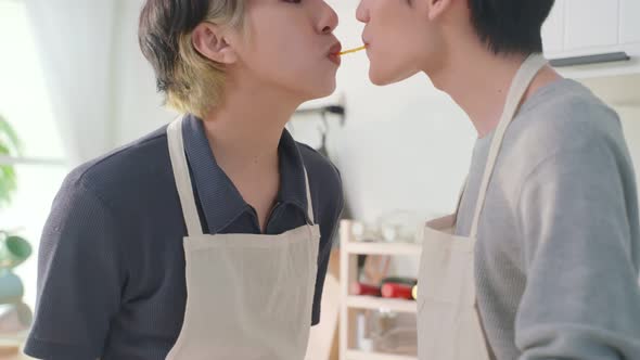 Asian handsome man gay family eating pasta by mouth to mouth together in kitchen in house. alt