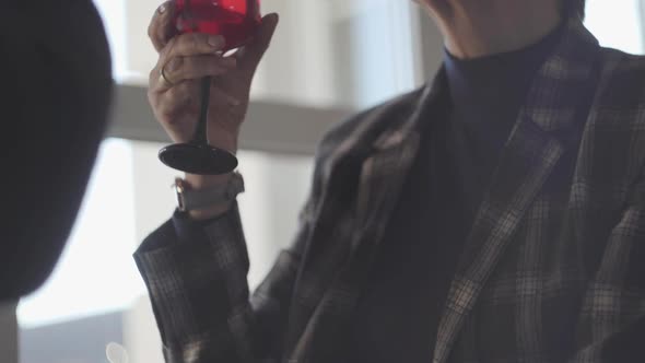 Unrecognized Adult Couple Drinking Wine From Glasses Sitting By the Wide Window alt