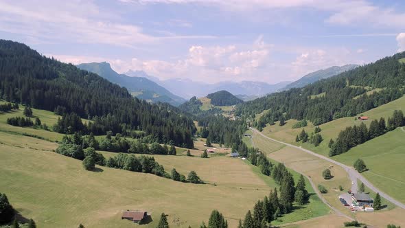 Aerial View of a Valley in Switzerland with Chalets and a Mountainous Landscape alt