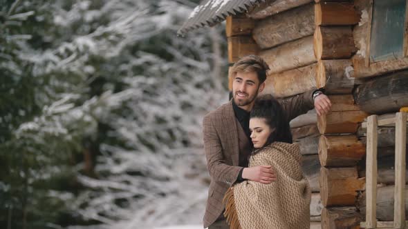 Couple Stands Near a Wooden House alt