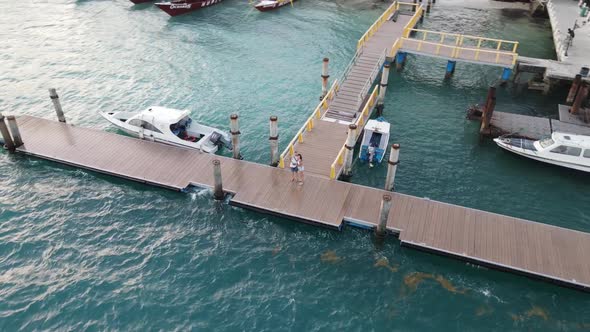 Sweet couple hugging on pier at harbor of Gili Air Island during holidays.Aerial circling shot. alt