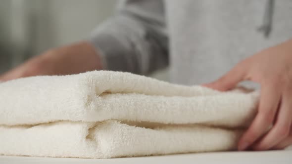 Young Woman Putting Washed Dry Clean Towels on Iron Board Preparing for Ironing alt