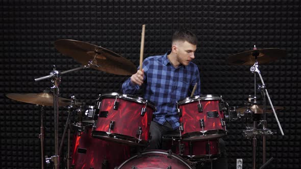 Musician drummer is playing on drum kit in recording studio alt