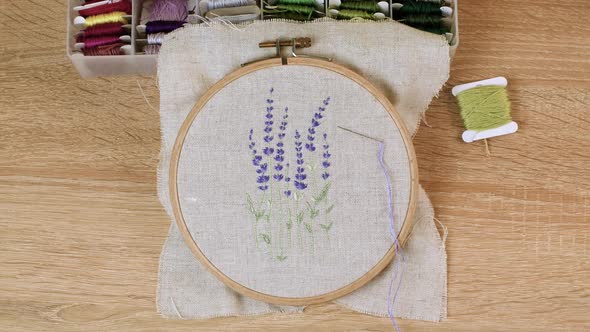 Woman makes embroidery a beautiful picture of lavender flowers. Handmade craft embroidery.