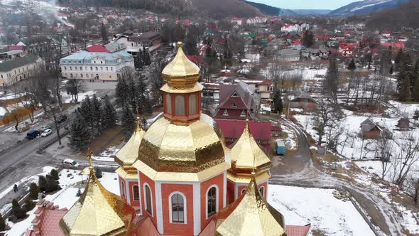 Aerial View of Ukrainian Church with Golden Domes in Carpathian Village in Winter alt