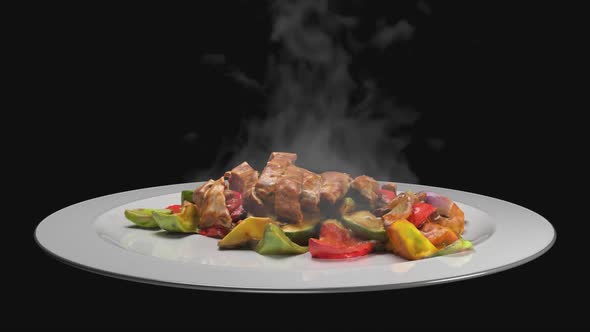 A delicious, hot plate of meat with vegetables from which steam is coming out against a shameful bac