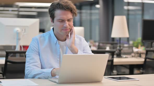 Man Having Toothache While Working on Laptop in Office alt