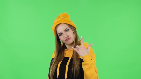 Portrait of Modern Girl in Yellow Hat Is Making a Rock Gesture and Enjoying Life alt