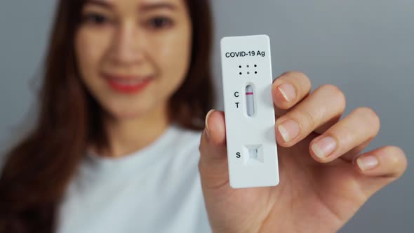happy woman holding Coronavirus(Covid-19) negative test result with Antigen Rapid Test kit (ATK)