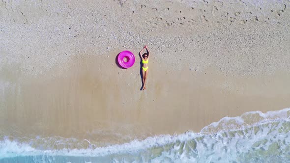 Aerial View of Young Woman with Pink Swim Ring on the Sandy Beach