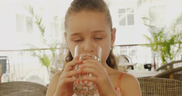 Cute Baby Boy Drinking a Glass of Water in a Cafe alt