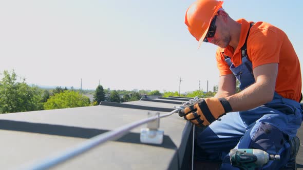 Technician Adjusting Metal Rod of Lightning Protection System on the Top of the Building. alt