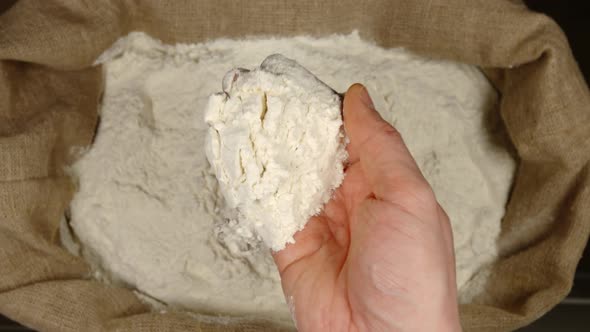 Human hand takes a handful of a wheat powder from a sac