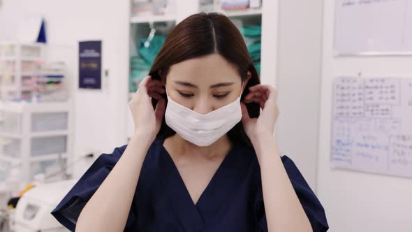 Portrait of beautiful young woman female doctor wearing medical face mask indoors in office. alt