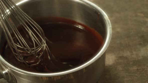 Closeup Metal Whisk Putting Into Melted Chocolate in Slow Motion. alt