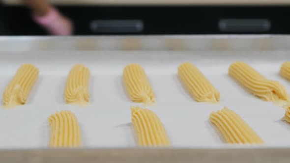 Choux Pastry Eclairs Before Baking in a Baking Sheet in Even Rows alt