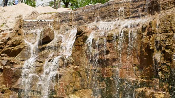 Beautiful waterfall from a cliff in the forest. Video of flowing water, flowing stream among stones alt