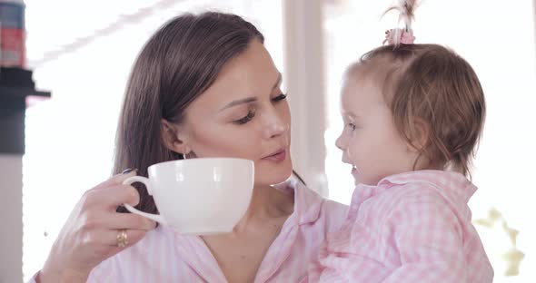 Mother with Daughter Standing at Kitchen and Drinking Coffee