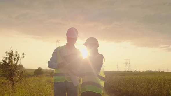 A Group of Engineers at a Highvoltage Power Plant with a Tablet and Drawings Walk and Discuss a Plan alt