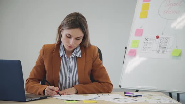Woman Creating New Mobile App Project and Making Notes on Paper
