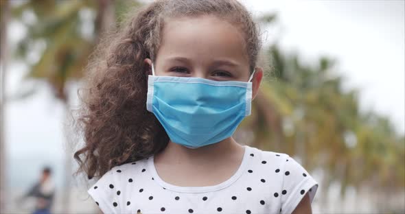 Cute Little Girl Standing on a Street in Protective Masks From the Covid-N1H1 Epidemic. Concept of alt