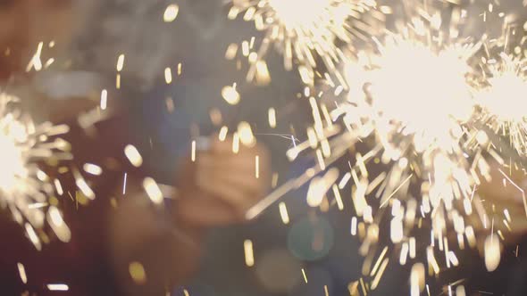 Close Up of Palms Lighting Latch or Fire Holding and Waving Sparklers alt