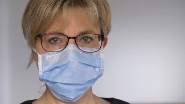 serious woman wearing the surgical mask staring at camera - corona virus alt