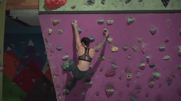 Follow Shot of Athletic Young Girl Training in Artificial Climbing Wall alt